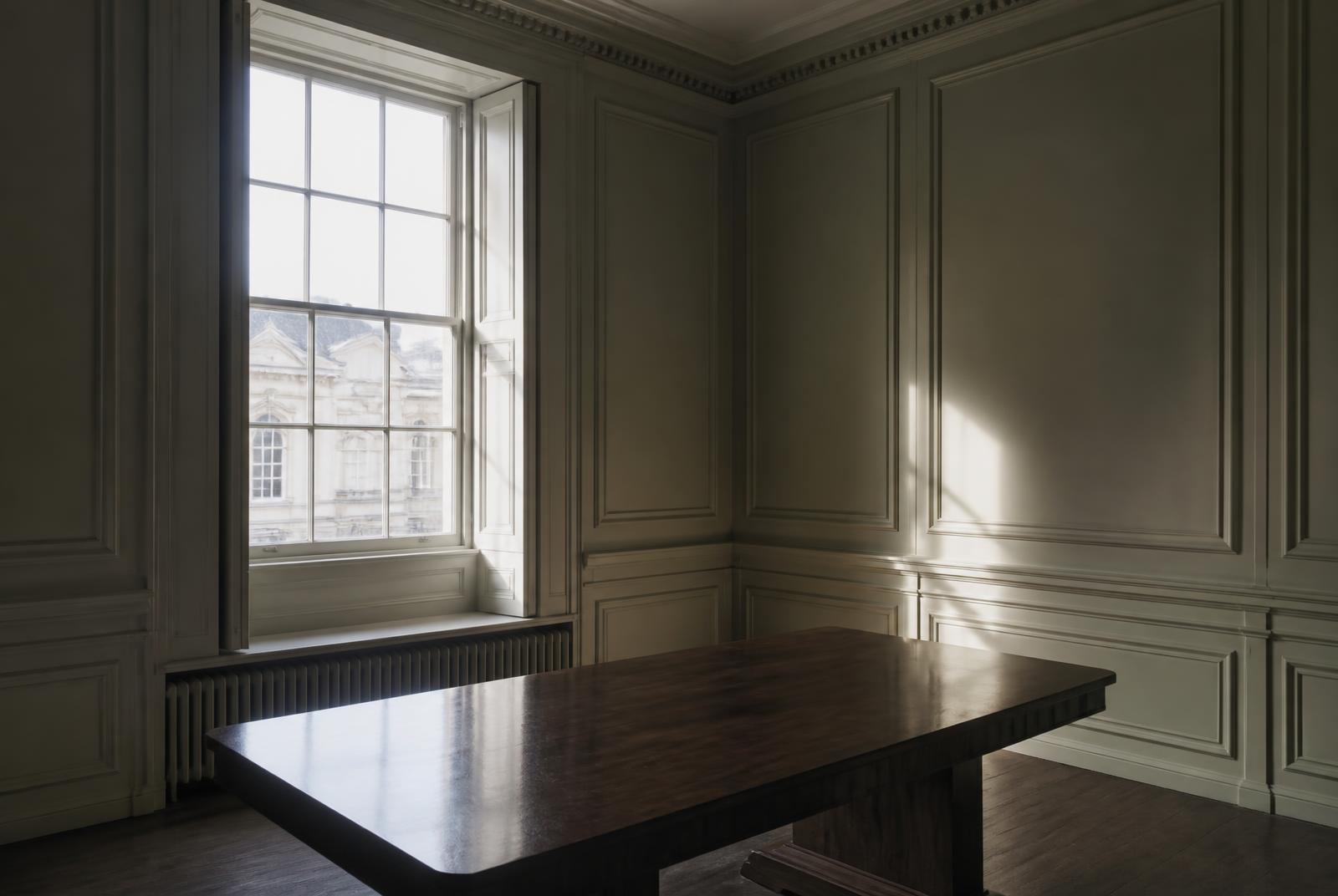 Panelled period room with daylight falling across a bare table